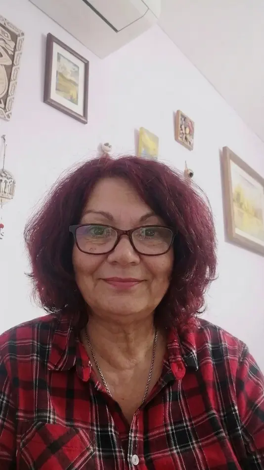 Дима Чонова с усмивка в карирана риза, гледаща към камерата